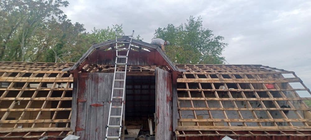 Barn before roof restoration — exposed framing and deteriorating roof
