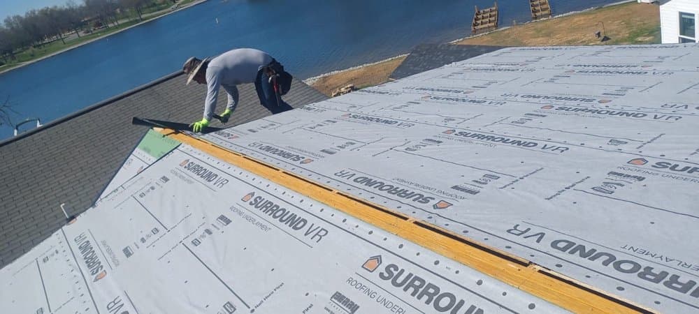 Worker installing roofing underlayment by the lake
