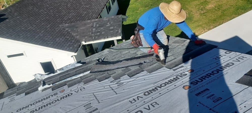 Roofer installing shingles over underlayment